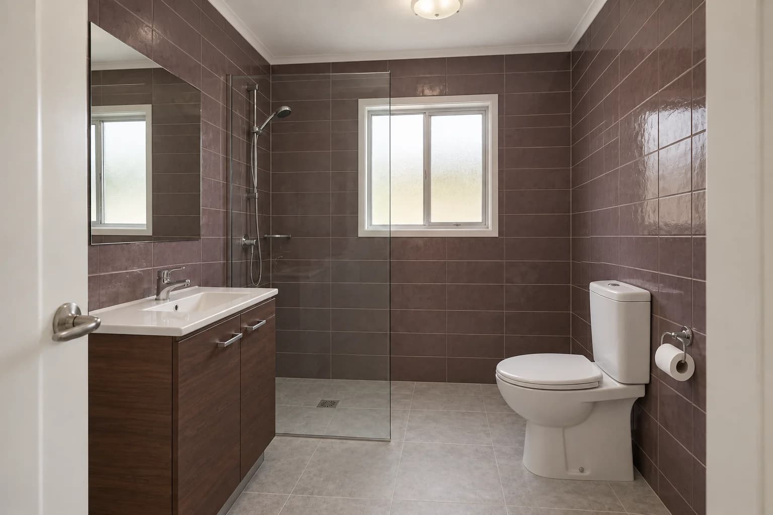 Muted plum-brown wall tiles, light grey floor and dark walnut vanity fronts.